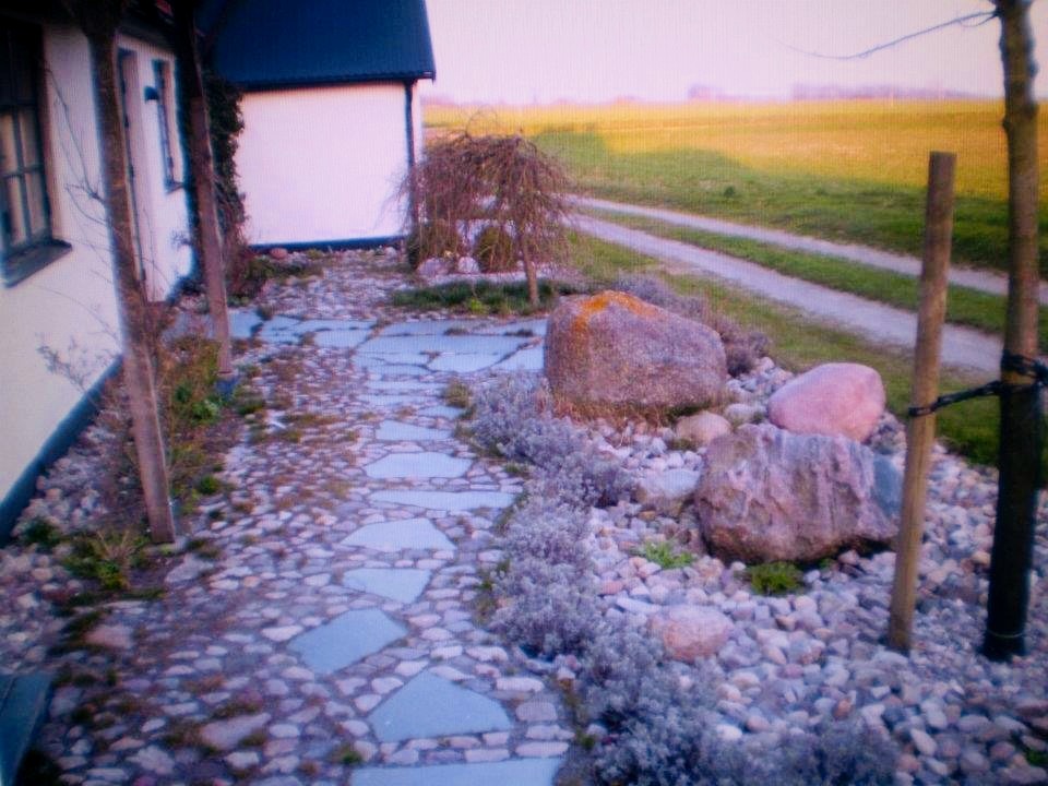 Stensatt gångväg i natursten utmed husgrund